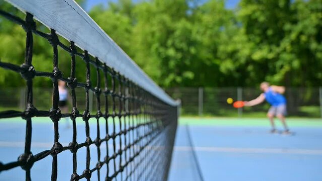 A man and a woman playing pickleball on a sunny day