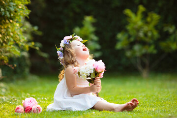 Little girl with flower bouquet in sunny garden