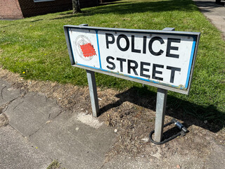 Post mounted Police Street name sign or street name plate on pavement or sidewalk on city road in the United Kingdom.