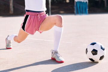 unrecognizable woman with a soccer ball stretching legs in a urban football court, concept of sport...