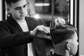 Haircut alignment of the contour of the head with scissors. Short haircut in the barbershop.