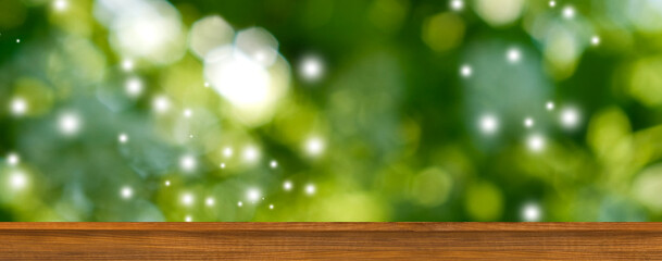 A wooden platform sits in front of a blurred background of green leaves with bokeh effects,...