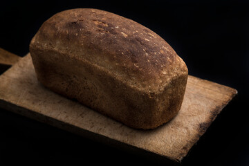 Brown bread on a wooden desk on dark background.