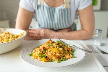 Fresh cooked healthy pan dish with couscous, chicken, beans and vegetables served by a woman with apron 