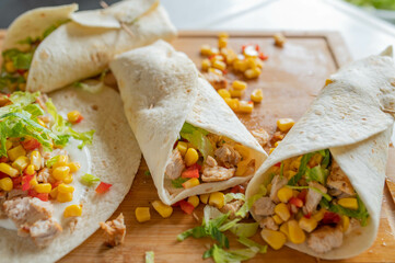 Healthy wraps or tortilla filled with pan fried turkey breast, corn and pepper salsa, sour cream and lettuce