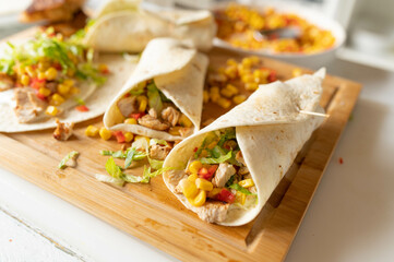 Healthy wraps or tortilla filled with pan fried turkey breast, corn and pepper salsa, sour cream and lettuce