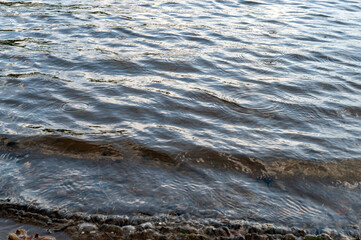 Rain drops on rippling lake water waves tranquil background with patterns and sunlight nature background