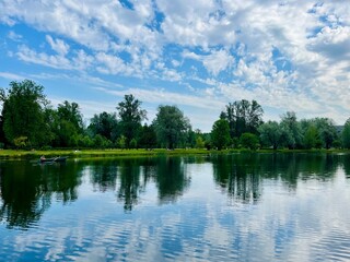 Green trees and sky reflection on the water surface, pond in the park
