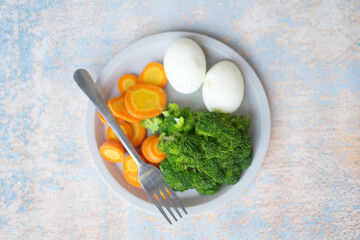 A breakfast diet plate without rice, featuring eggs, carrots, and broccoli, promoting a healthy and balanced meal
