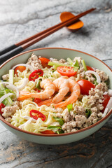 Thai salad with instant noodles, shrimp, minced pork and vegetables close-up in a bowl on the table. Vertical