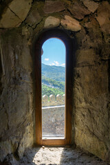 External stone wall and mountains seen through a narrow window of a church in a Dzama fortress