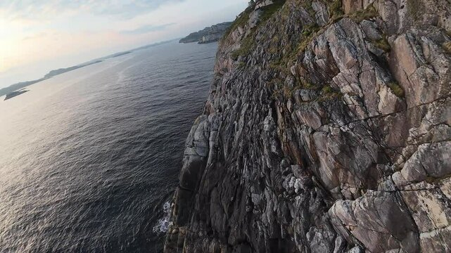 FPV aerial cruising close to coastal island at sunset near Sotra and Bergen, Norway