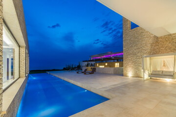 A modern house with a swimming pool located at its center, creating a unique and visually striking architectural design. The pool serves as a focal point of the house, seamlessly integrated into its s