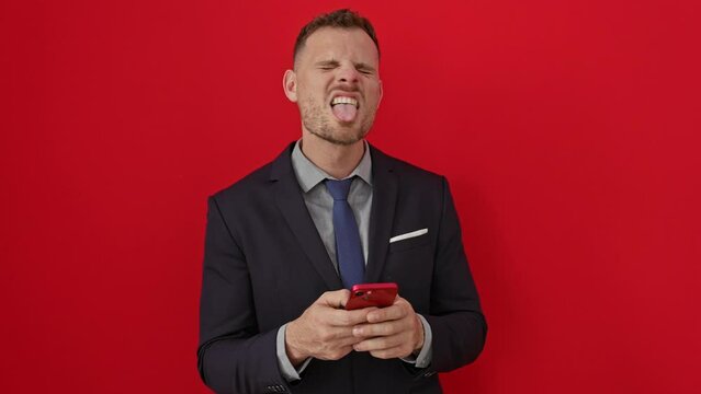 Young hispanic man in suit, happy and funny sticking tongue out, over isolated red background