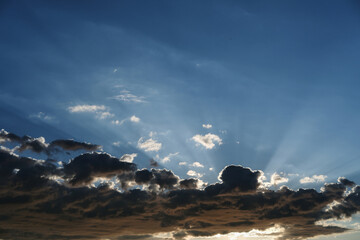 the sun's rays are visible through the clouds. blue sky with clouds and sun rays.
