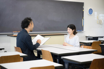 学校や塾との保護者面談のイメージ　子どもの成績が良くて喜ぶ親　進路や塾の相談のイメージ広角