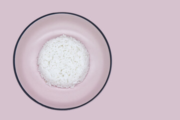 Cooked rice isolated on pink background. Top view pink bowl of jasmine rice with pink background. Concepts of healthy food, vegan, organic ingredient, and cooking. Rice bowl isolated and copy space.