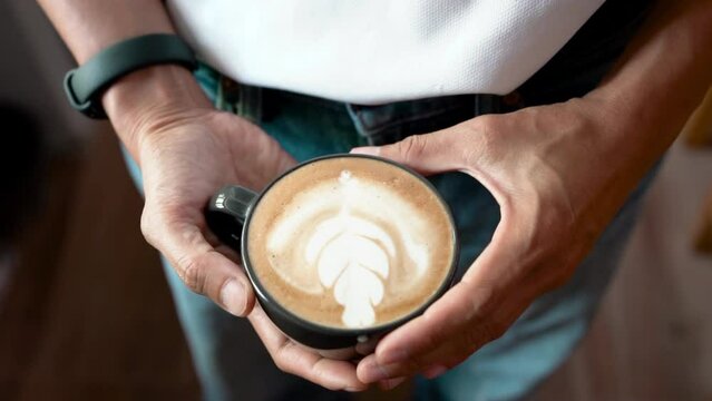 Hand of barista holding cup of latte art homemade coffee. top view 4K video