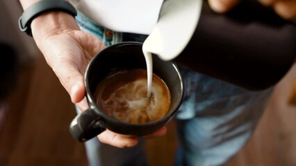 Preparation, Top view person's hand is using a pitcher to pour milk foam to make a hot coffee latte. Making homemade coffee at home. Close up slow motion video