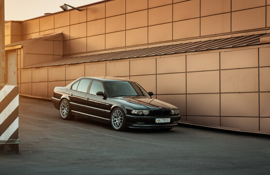 Black BMW 7-series (E38) sedan parked near beige brown-bronze wall. Three quarter front view of 1990s executive car. Kyiv, Ukraine - September 24, 2015.