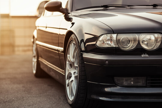 Black BMW 7-series (E38) sedan at sunset. Close up view of front right corner of the 1990s executive car. Kyiv, Ukraine - September 24, 2015.