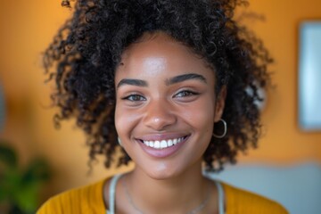 Woman smiling with curly hair in a yellow shirt