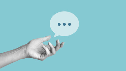 Hand on blue background holding a message icon, bubble talk or notification sign. Chat icon, sms icon in speech bubble, comments icon