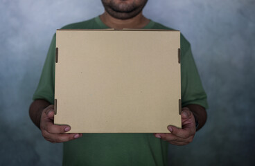 Close up of man with cardboard box parcel. Young man carry brown box sending delivery service...