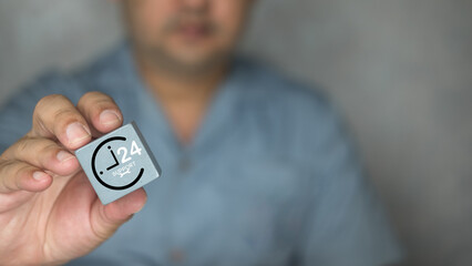 Fototapeta premium Technician man show wood block with an icon of nonstop service. The concept of online technical support, customer service 24/7 nonstop. Technical support customer service call center