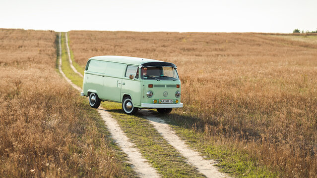Green classic Volkswagen Transporter van on countryside unpaved downhill road, three quarter view. Kyiv region, Ukraine - September 15 2015.