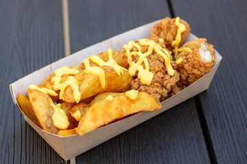 Fast food dish of french fries and chicken in a cardboard container