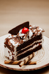 Close-up of a Delicious Chocolate pastry with a cherry and chocolate wafer on top. On a white plate. Front view.