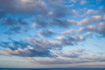 Fototapeta premium The sky is cloudy and the ocean is calm. The clouds are scattered throughout the sky, creating a sense of movement and depth