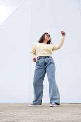 plus size woman wearing casual clothes dancing on white wall background in the street