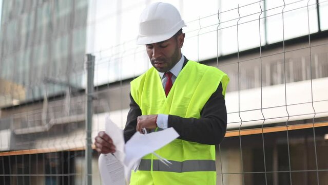 Angry architect tearing documents at construction site.