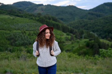 Young tourist woman traveller with backpack walking in nature. Active hiker on trail in mountains enjoying sunset.