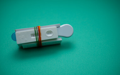A few of Covid-19 rapid antigen test casettes tied with colorful rubber bands, isolated on green background. A close-up and selective focus photo of the test cassette. 
