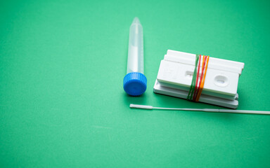 A few of Covid-19 rapid antigen test cassettes (tied with colorful rubber bands) with a swab stick...
