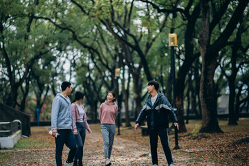 young Asians walk outdoors, sharing their recent exercise experiences as they stroll. They also use reusable water bottles, embodying the concept of sustainable living.