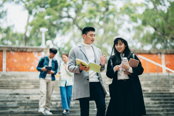 Asian university students walk out of the classroom, discussing their coursework as they walk, presenting the campus atmosphere.