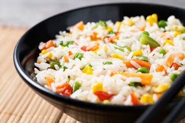 White fried rice with vegetables on wooden table.Close up 