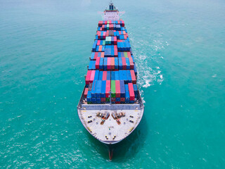 Fototapeta premium the aerial perspective of a cargo ship being loaded and unloaded at a bustling seaport and sailing out of the mainland