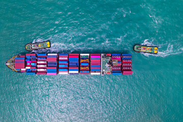 the aerial perspective of a cargo ship being loaded and unloaded at a bustling seaport and sailing...