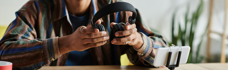 A young African American male blogger is creatively engaging with a headset on a table. - Powered by Adobe