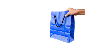 A person's hand seen holding a blue crumpled shopping bag against a black background, suggesting a shopping theme