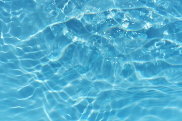 Obraz premium Blue water with ripples on the surface. Defocus blurred transparent blue colored clear calm water surface texture with splashes and bubbles. Water waves with shining pattern texture background. 