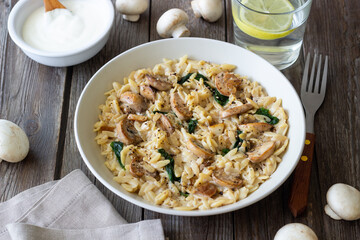Orzo pasta with mushrooms and spinach. Italian Cuisine. Vegetarian food.
