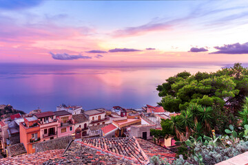 Fototapeta premium sceniv view from a high mountain town to amazing landscape of sea coast, roofs in vintage style of Italy and beautiful colorful sunset or sunrise cloudy sky