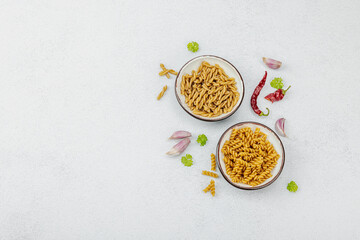 Pasta. Various kinds of uncooked pasta and noodles over light stone background. Traditional Italian