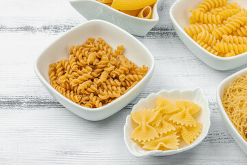 Pasta. Various kinds of uncooked pasta and noodles over wooden background